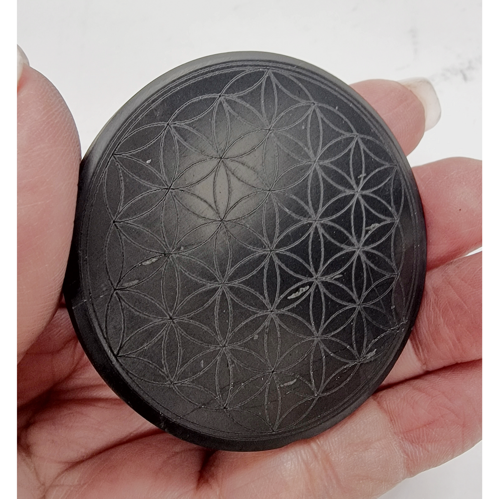 Shungite round 50mm Flower of Life engraved protective slice on hand, grounding and EMF protection crystal