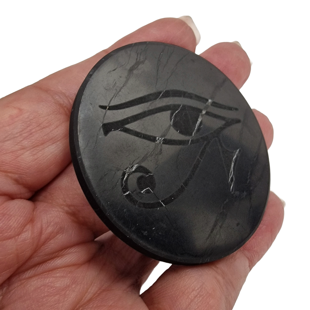 Shungite round 50mm Eye of Horus engraved protective slice on hand, grounding and EMF protection crystal