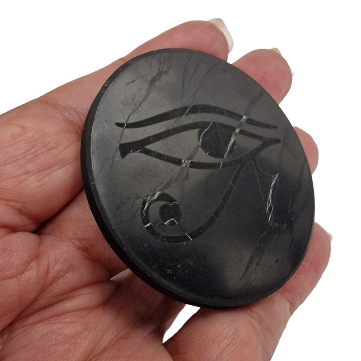 Shungite round 50mm Eye of Horus engraved protective slice on hand, grounding and EMF protection crystal