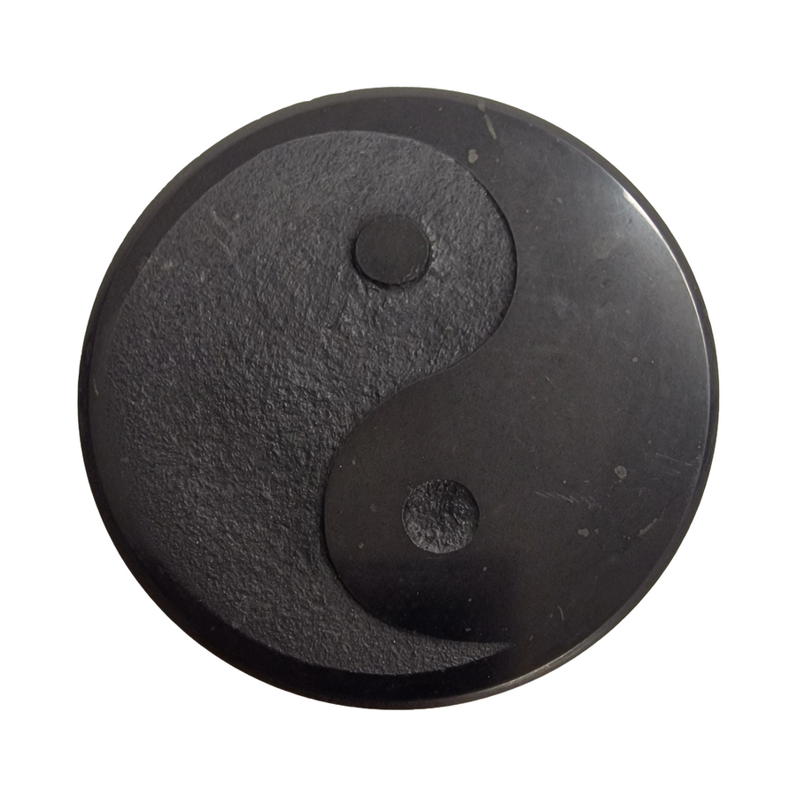 Shungite round 50mm Yin Yang slice on white background, energy balancing crystal for electronics