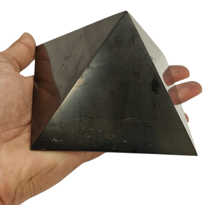 Shungite 10cm square Yin Yang charging disc on hand for size reference, grounding and EMF protection crystal