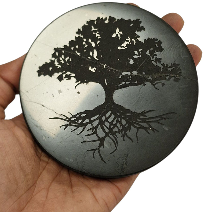 Shungite 10cm round Tree of Life charging disc on hand for size reference, grounding and EMF protection crystal