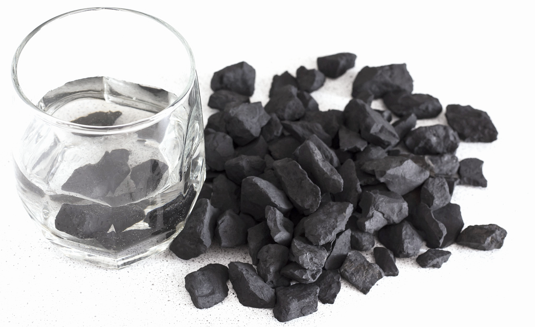 Petrovsky Shungite crystals arranged beside glass of water