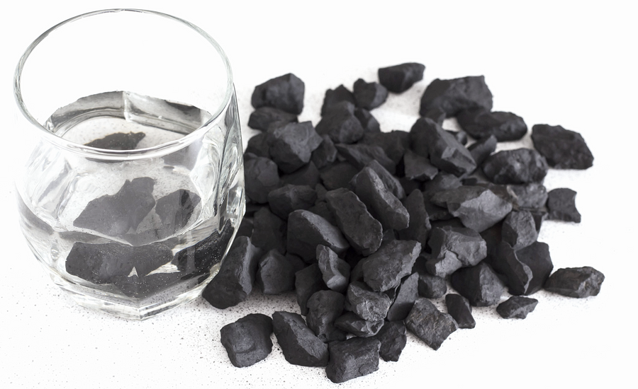 Petrovsky Shungite crystals arranged beside glass of water