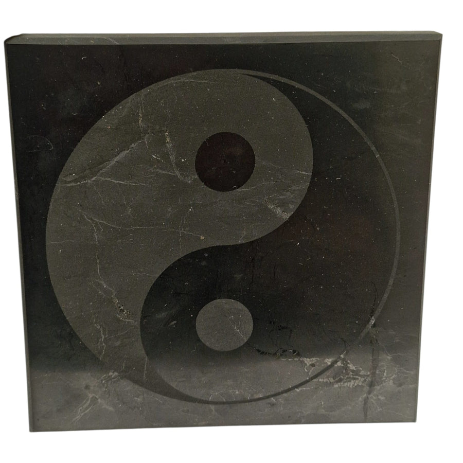 Shungite 10cm square disc with Yin Yang engraving on white background, crystal charging plate for harmony and balance