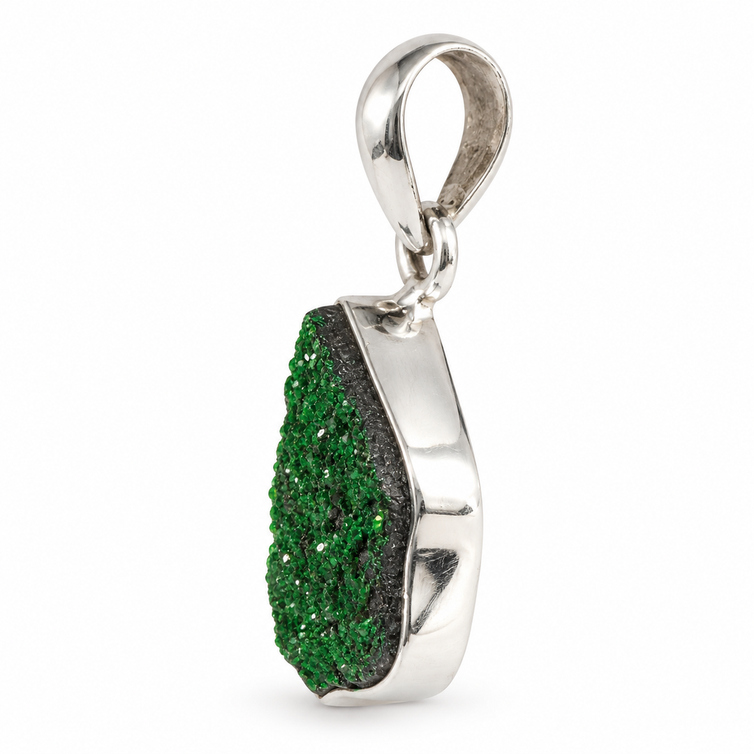 GeoFossils Uvarovite Garnet pendant from the opposite side, highlighting the depth of its crystalline green surface and substantial silver bezel setting.