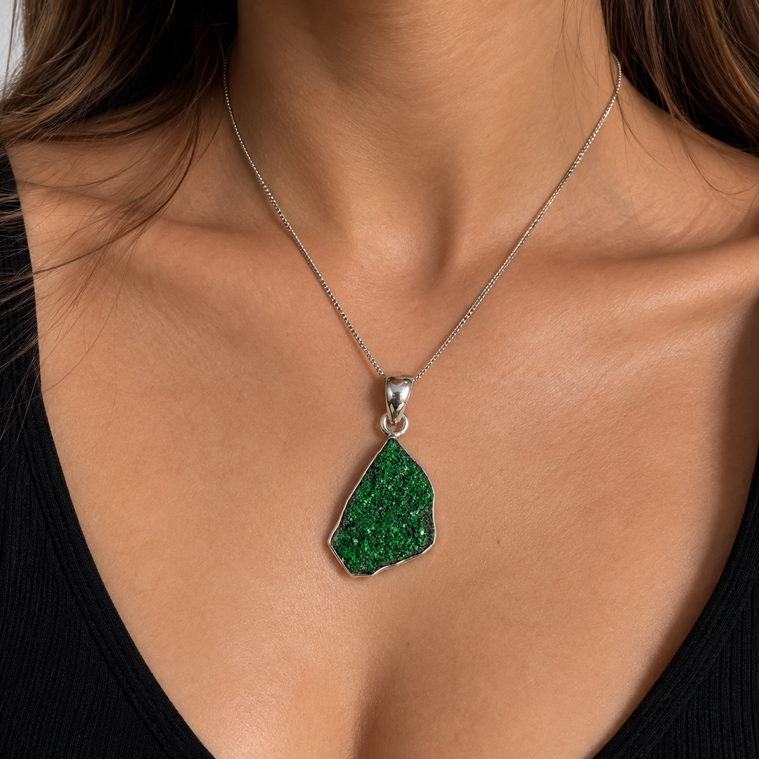 GeoFossils natural Uvarovite Garnet pendant worn on a fine silver chain by a female model, showcasing the emerald-green crystalline gemstone against the neckline.