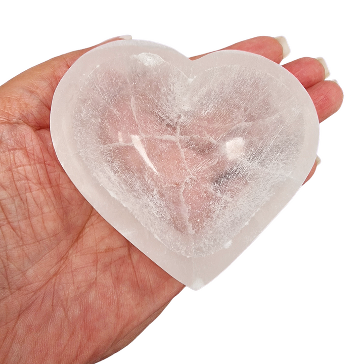Selenite Charging Bowl 8 cm heart shape shown on hand for scale.