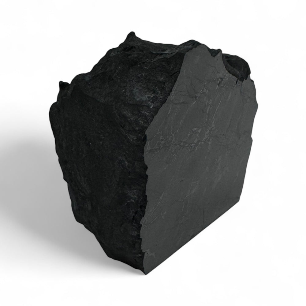 Angled view of a raw shungite crystal with one polished surface, used for grounding and radiation shielding.