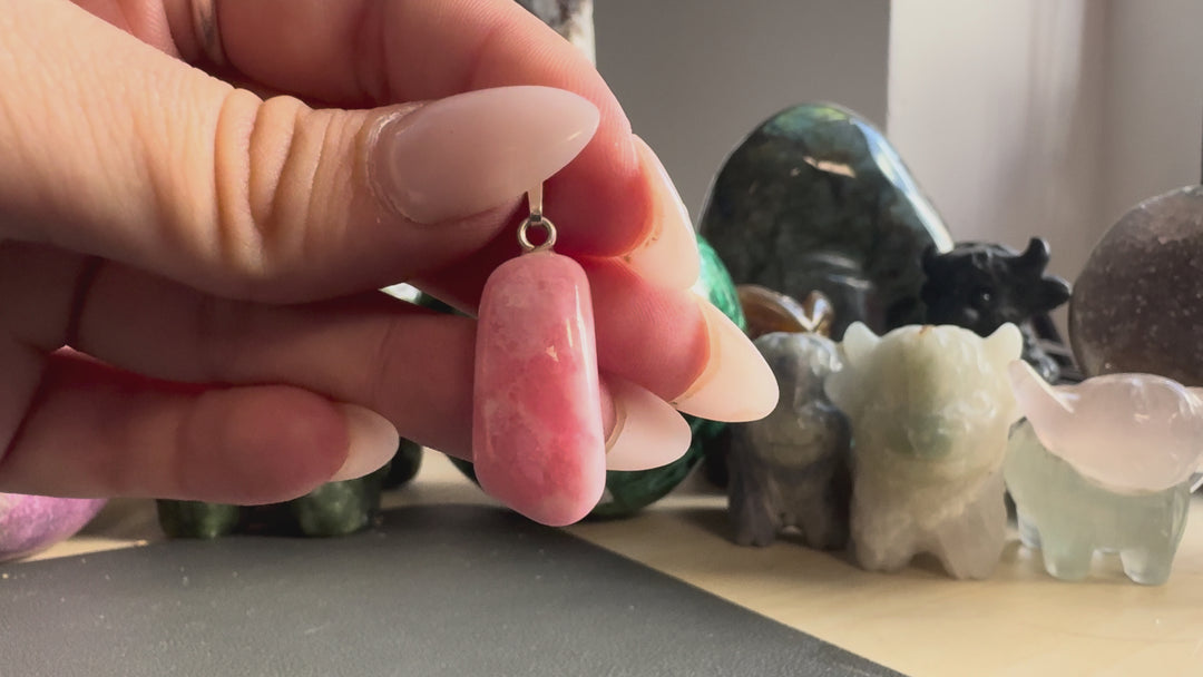 GeoFossils natural Rhodochrosite pendant product video showcasing its polished rose-pink gemstone, natural white marbling, rounded elongated shape and 925 sterling silver bail.
