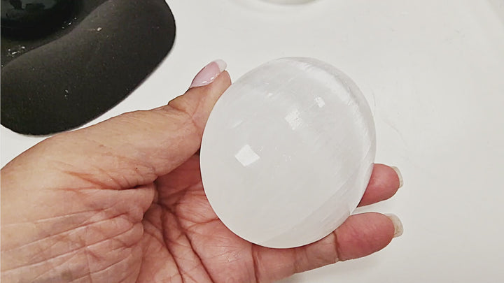 13-second video showing three Selenite Palm Stones in 50 mm, 70 mm, and 90 mm sizes. Each stone is displayed individually in hand, with a group shot of all three sizes resting together on the palm to show scale.