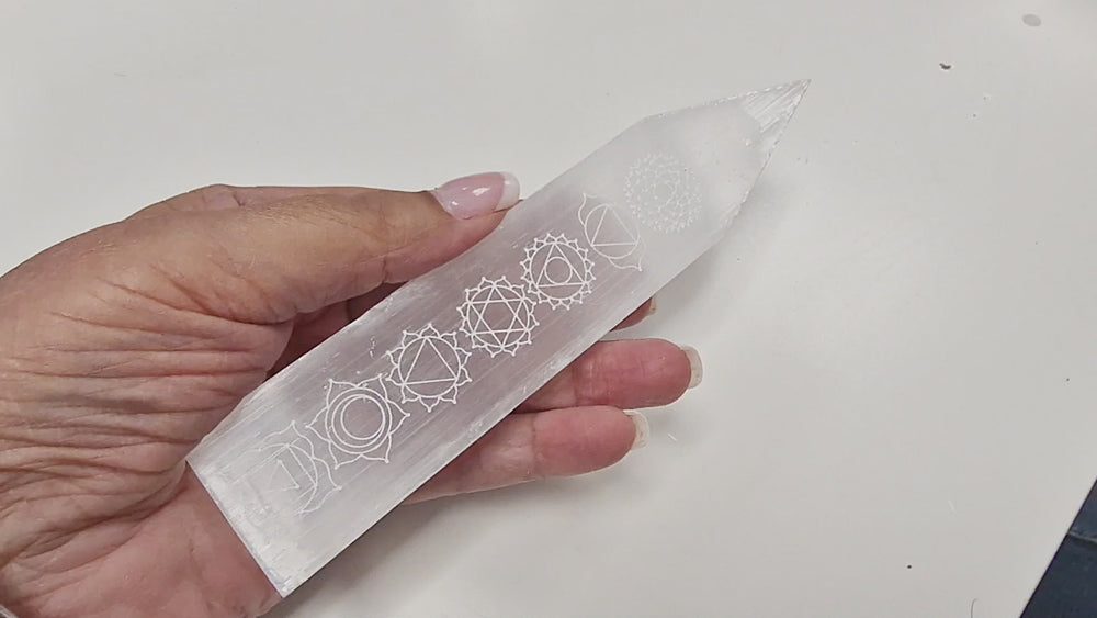 18-second video of a Selenite Chakra Blade – Engraved Polished Wand being held and rotated in hand to display the engraved chakra symbols, polished blade-like sides, and pointed tip from all angles.