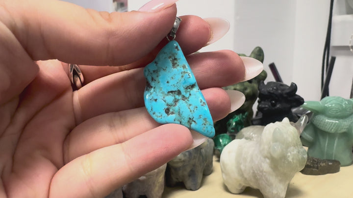 GeoFossils video showcasing the one-of-a-kind Kingman Mine Turquoise pendant from Arizona, USA, highlighting its vibrant sky-blue colouration, natural dark brown and black matrix patterns, polished freeform shape and 925 sterling silver bail from multiple angles.