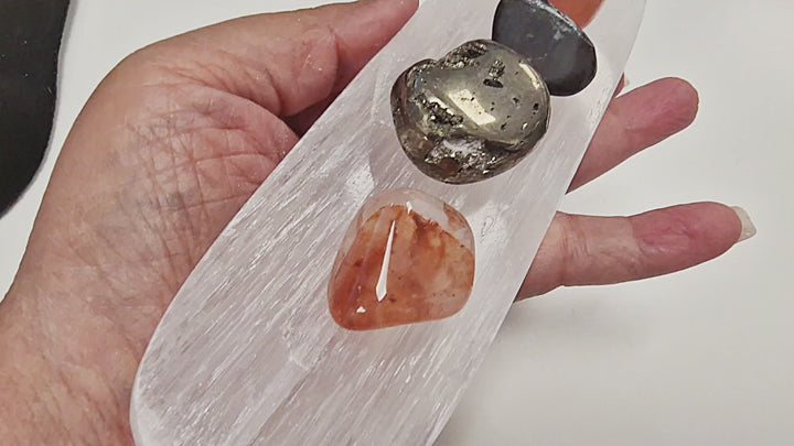 25-second video of a Selenite Charging Tray with Groove being held and rotated to show its elongated dish shape, central groove, and luminous polished surface from all angles. Crystals are placed for demonstration but are not included.