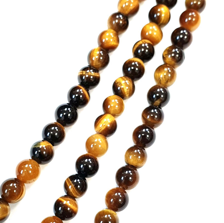 Gold Tigers Eye round beads on a white background 6mm